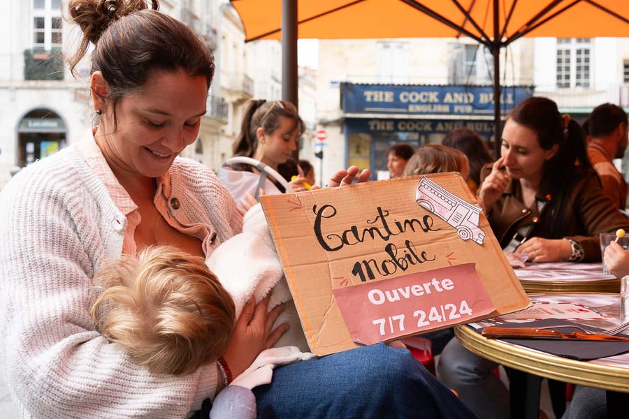 Une maman allaitant son bébé, avec une pancarte Cantine Mobile, lors de JFJM 2025 Bordeaux