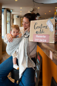 jaifaimjemange-bordeaux-2025-marion-ziade-33 Une maman portant son bébé en sling, avec une pancarte Cantine Mobile, lors de JFJM 2025 Bordeaux