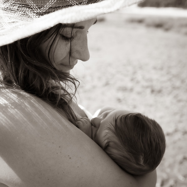 Maman allaitant son bébé à la plage.